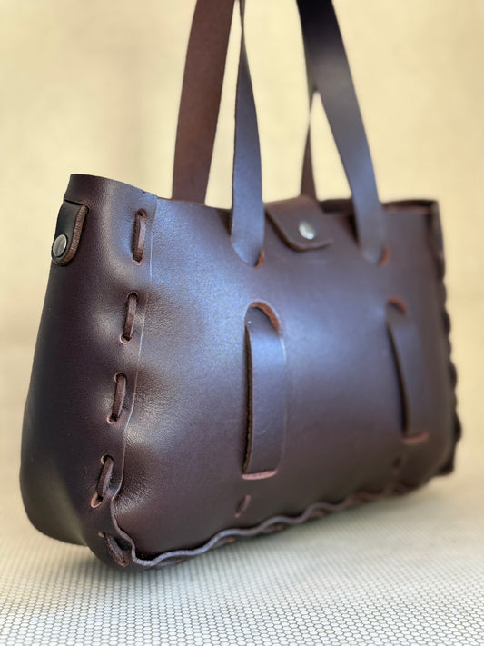 Brown Dean leather handbag with decorative stitching on a light background