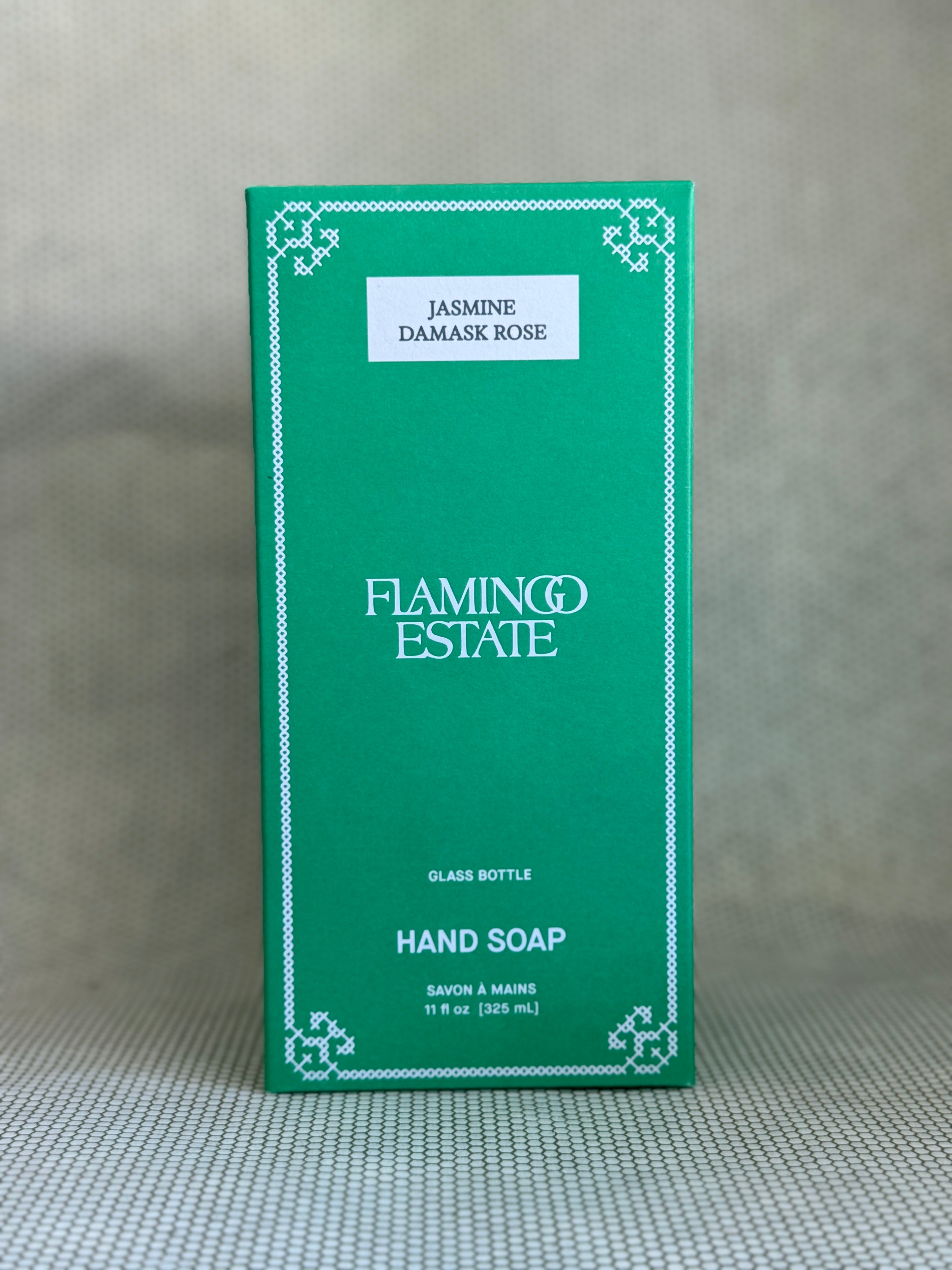Green box of Flamingo Estate Jasmine Damask Rose hand soap on a textured surface.