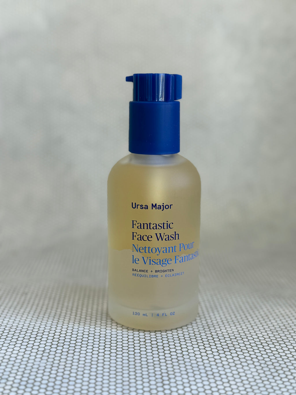 glass bottle of Ursa Major Fantastic Face Wash with pump on a textured gray background