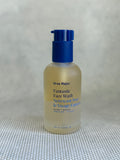 glass bottle of Ursa Major Fantastic Face Wash with pump on a textured gray background