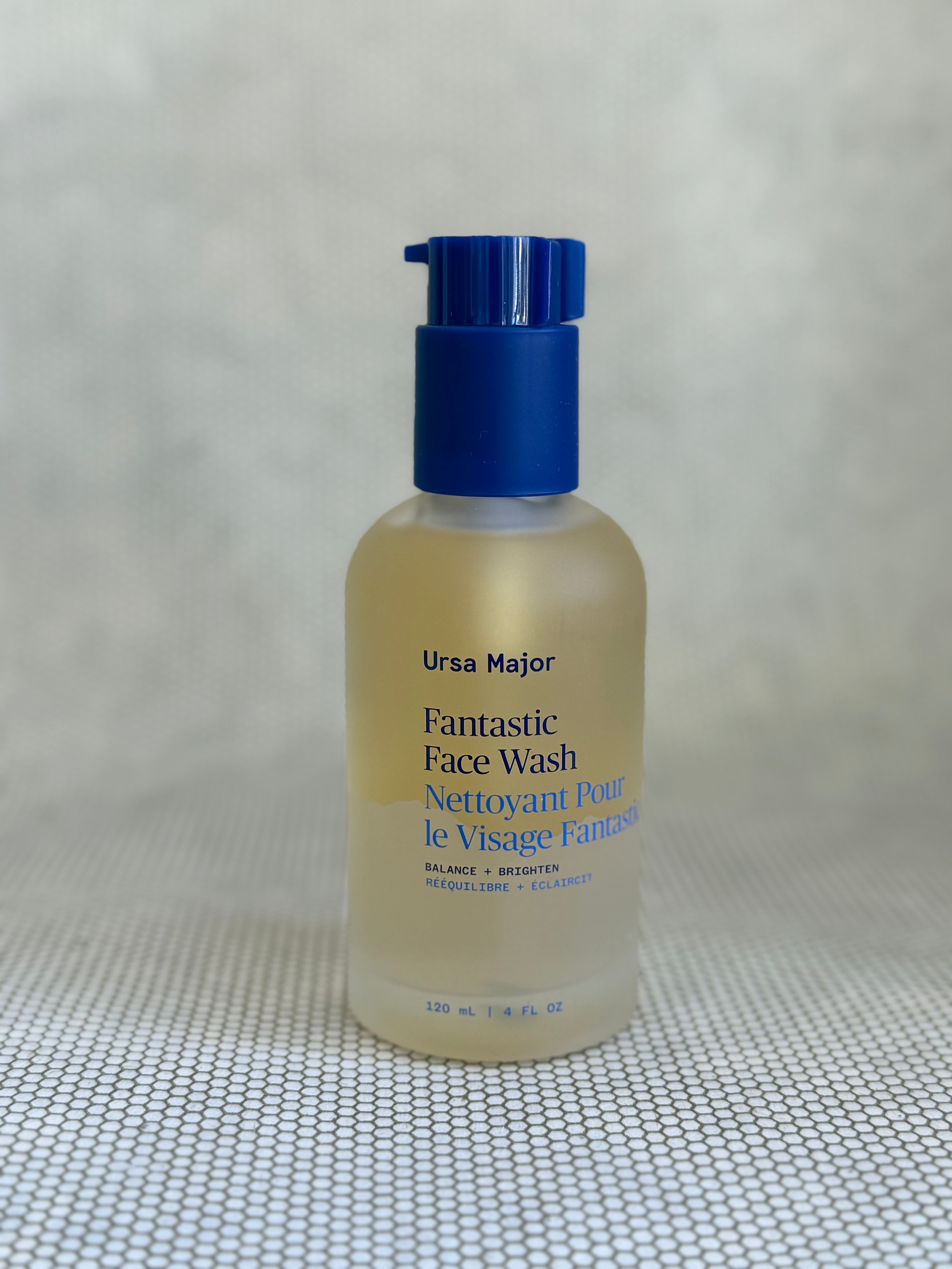 glass bottle of Ursa Major Fantastic Face Wash with pump on a textured gray background