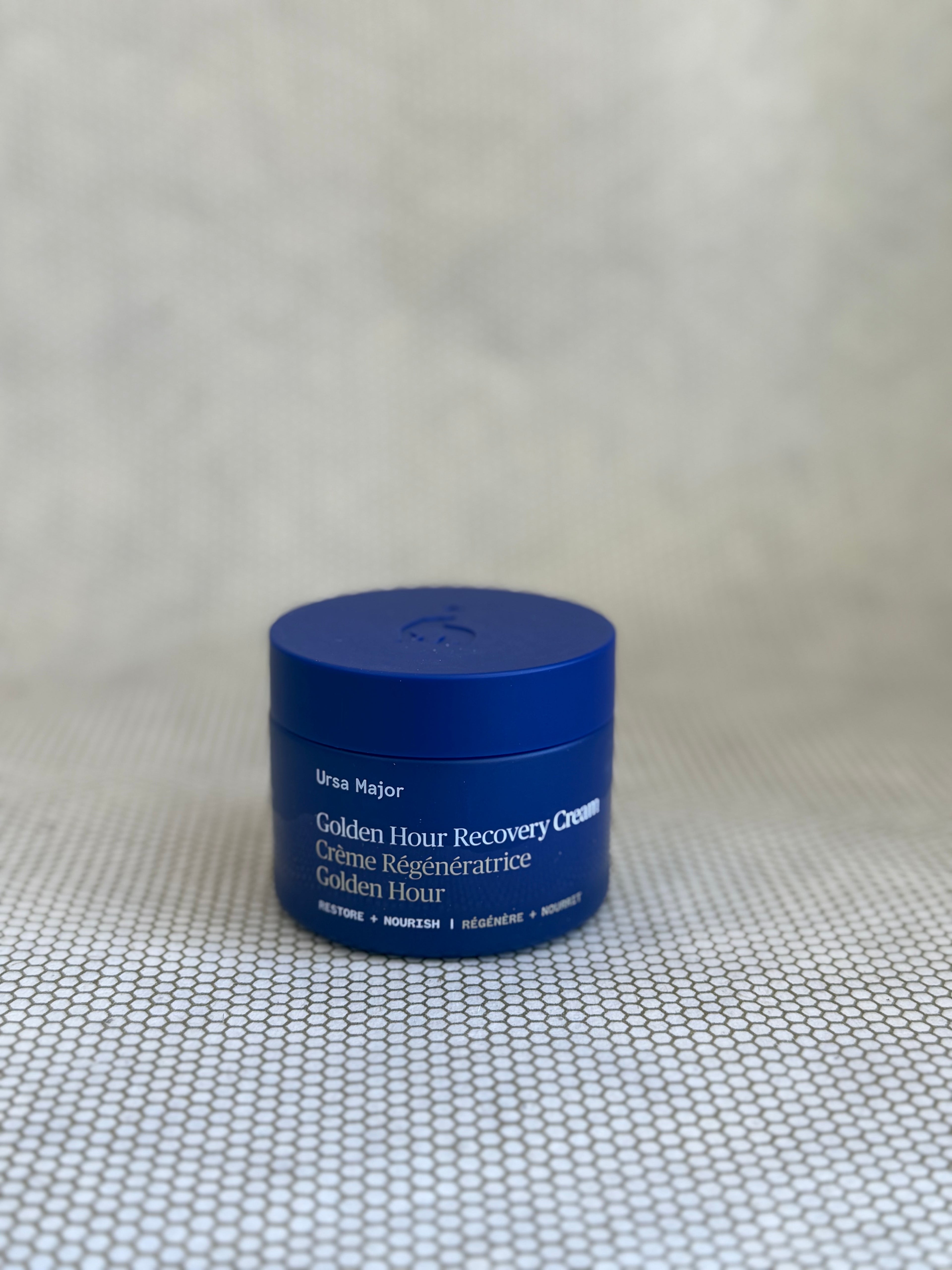 Blue jar of Ursa Major Golden Hour Recovery Cream on neutral background. 
