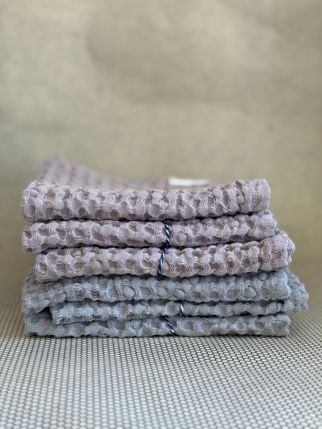 Stack of gray and pink textured towels on a neutral background