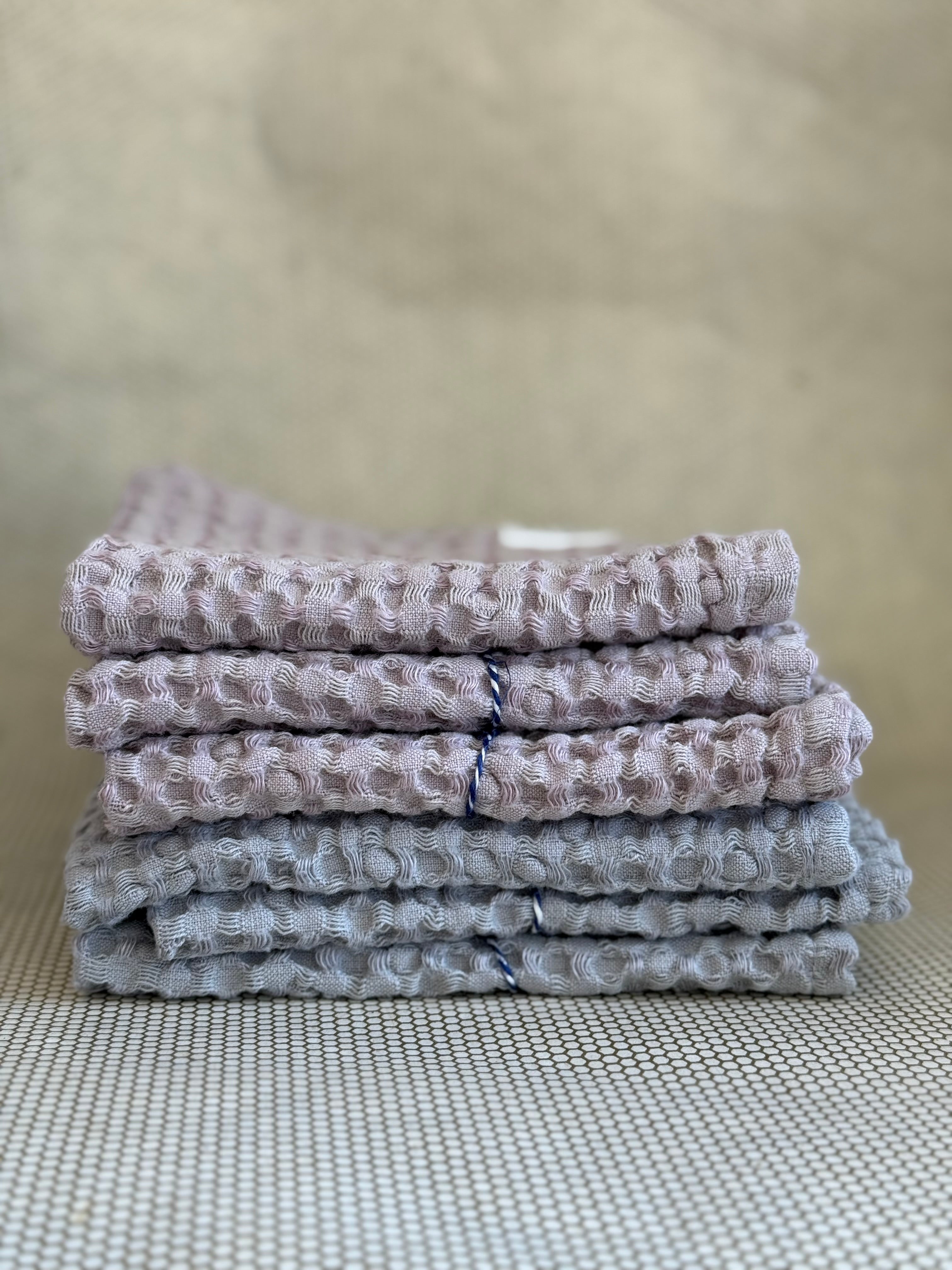 Stack of gray and pink textured towels on a neutral background