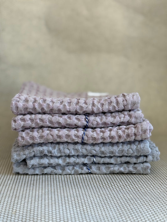 Stack of gray and pink textured towels on a neutral background