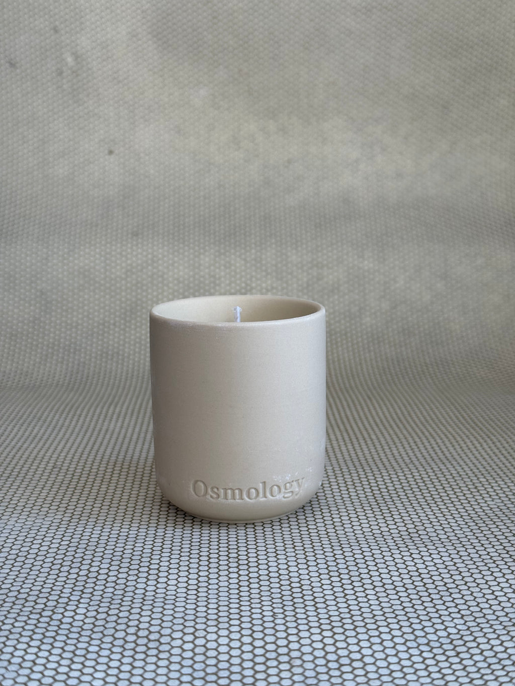 cosmology himalayan cedarleaf votive candle in neutral ceramic container on neutral background. 