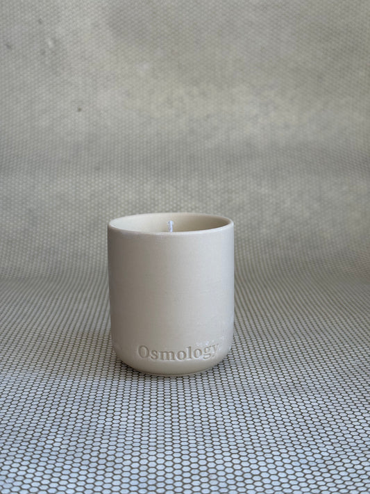 cosmology himalayan cedarleaf votive candle in neutral ceramic container on neutral background. 