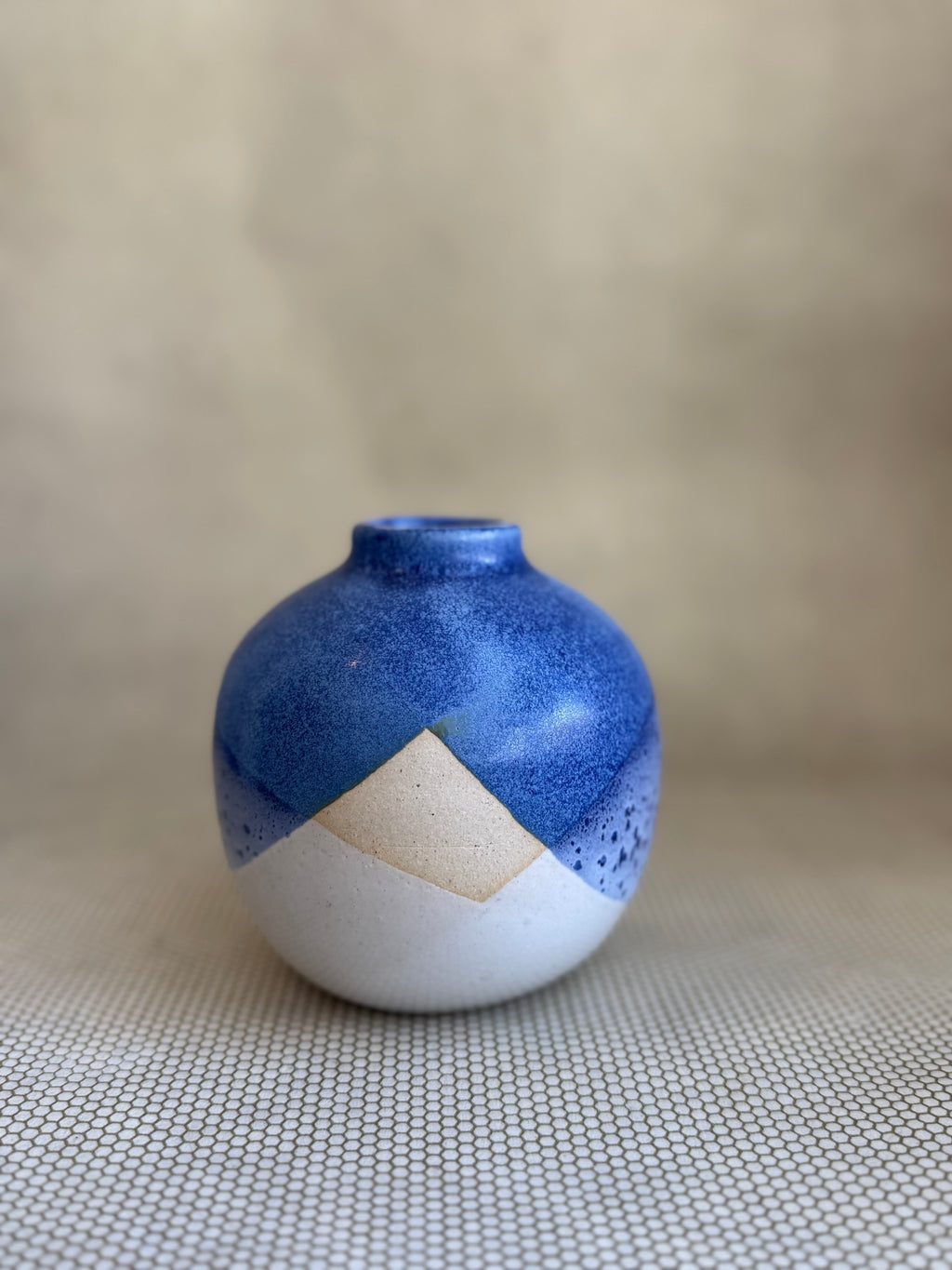 Blue and white ceramic vase on a textured surface with a neutral background