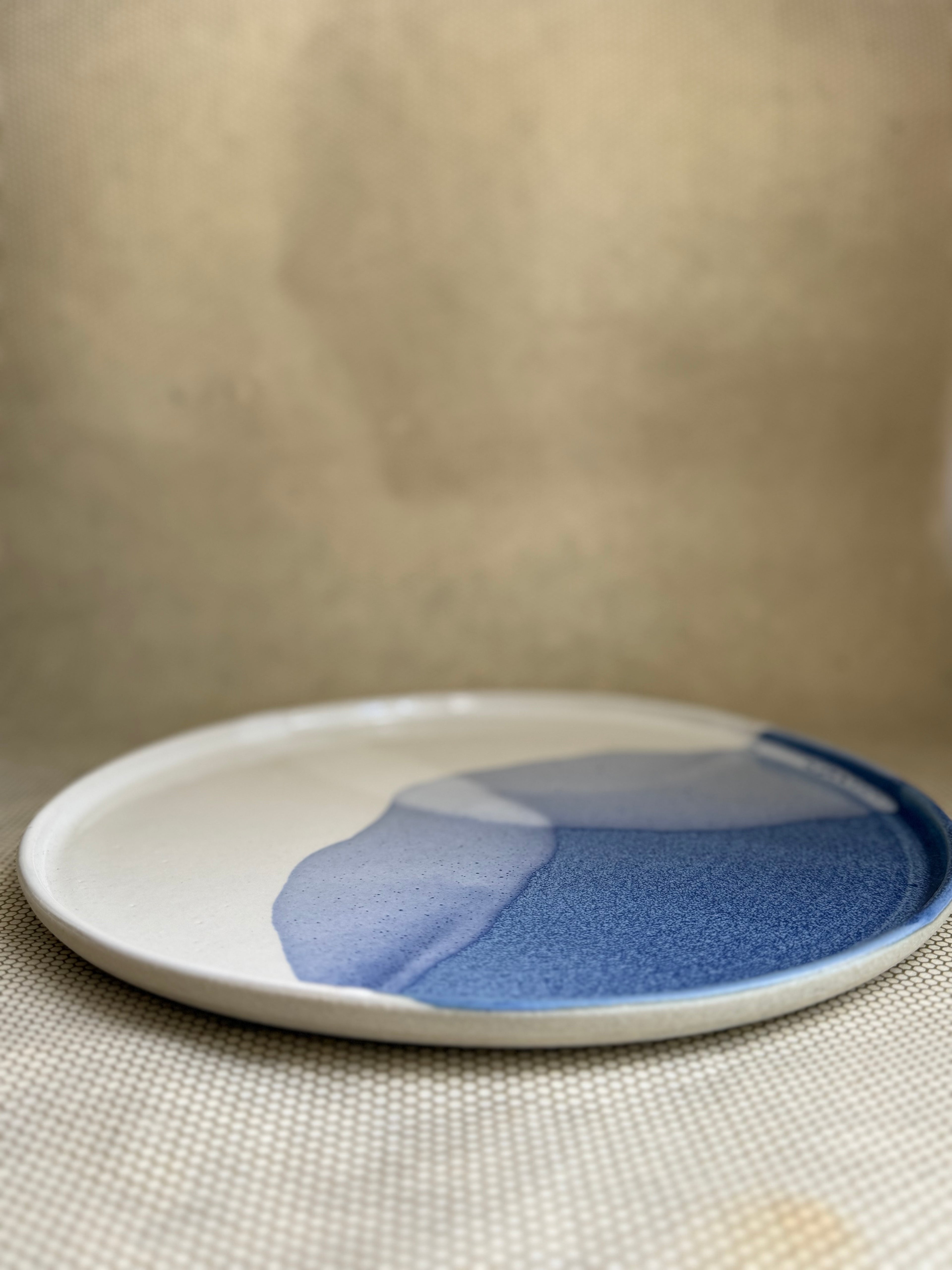 handcrafted ceramic plate with blue and white design on a beige surface.