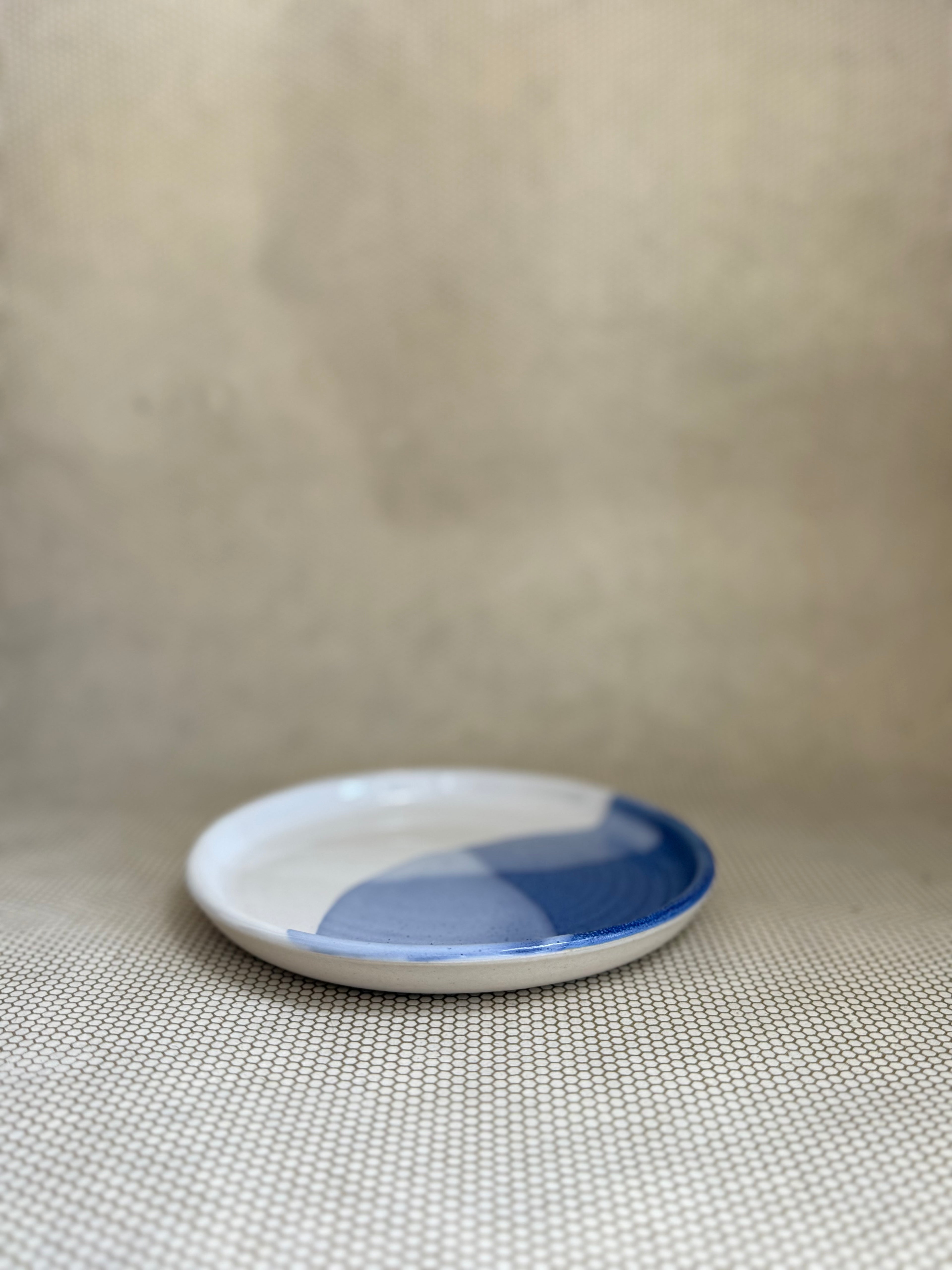Small ceramic plate with blue and white design on a beige background.