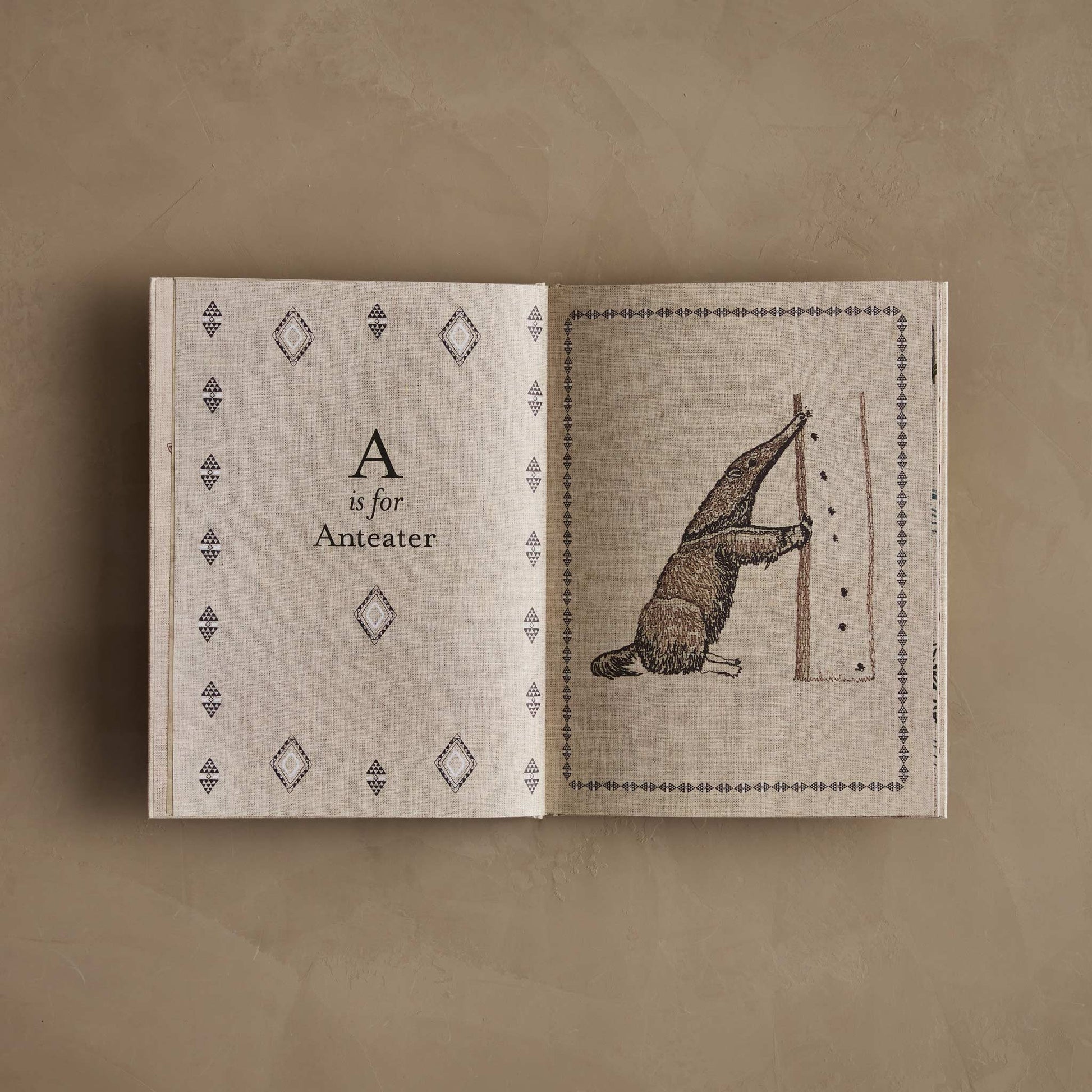 Open book showing 'A is for Anteater' on a beige background